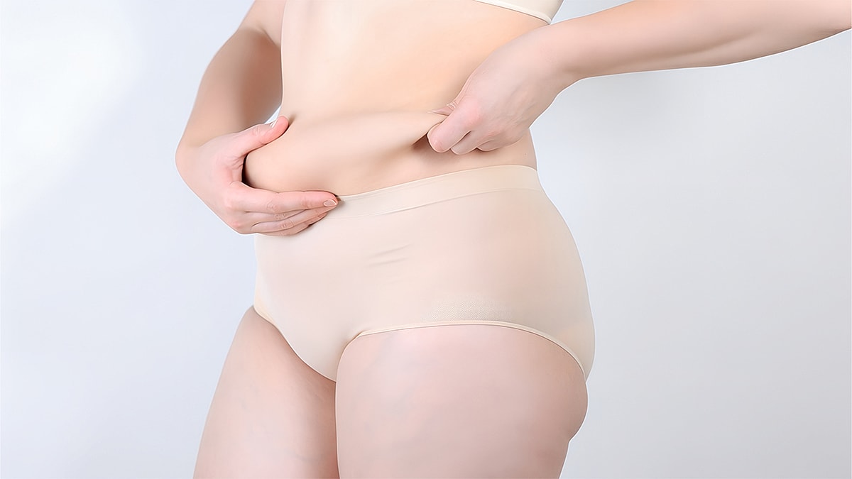 What Causes a Hanging Belly Featured Image - Woman adjusting waistband of high-waisted underwear.