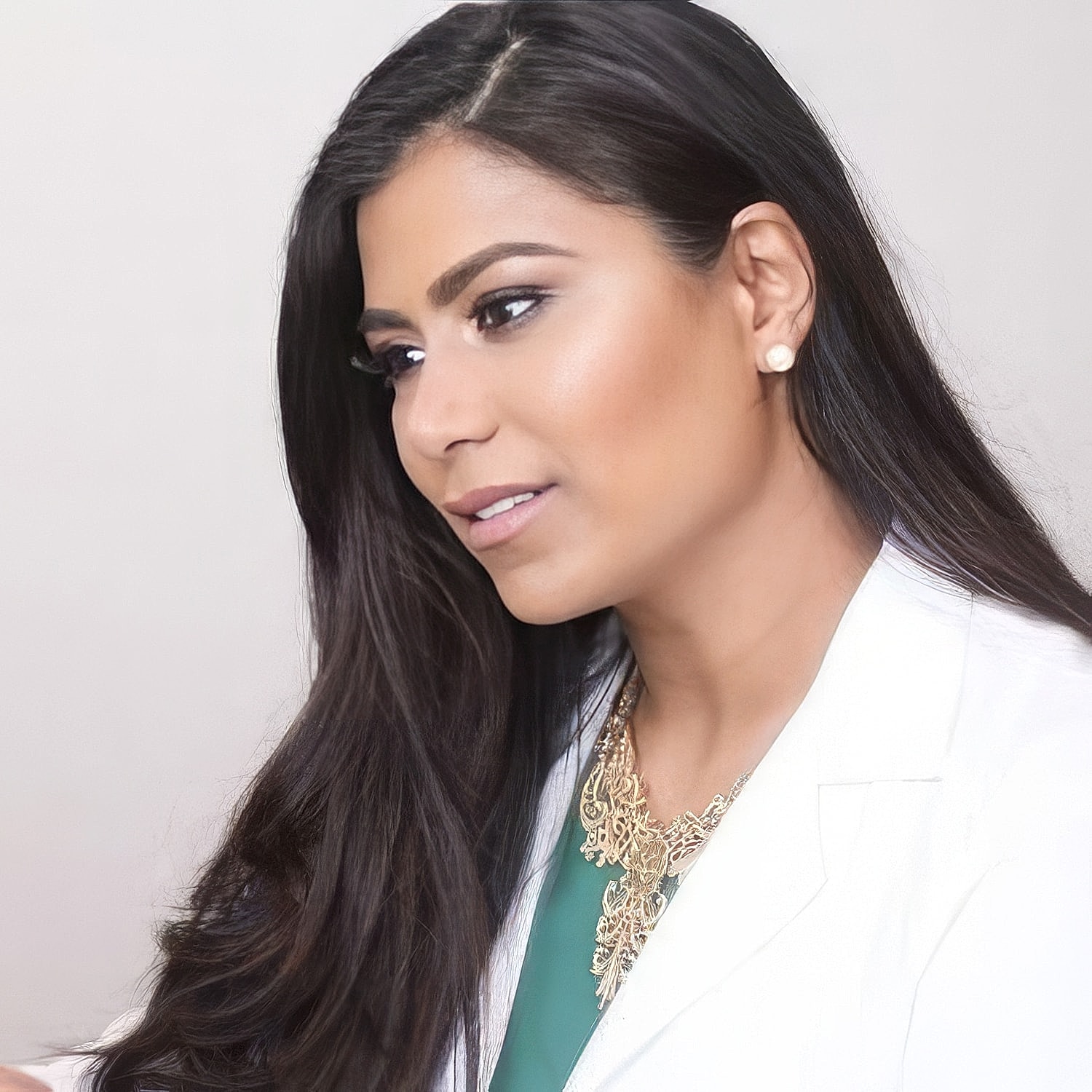Professional woman in a white coat, smiling softly.