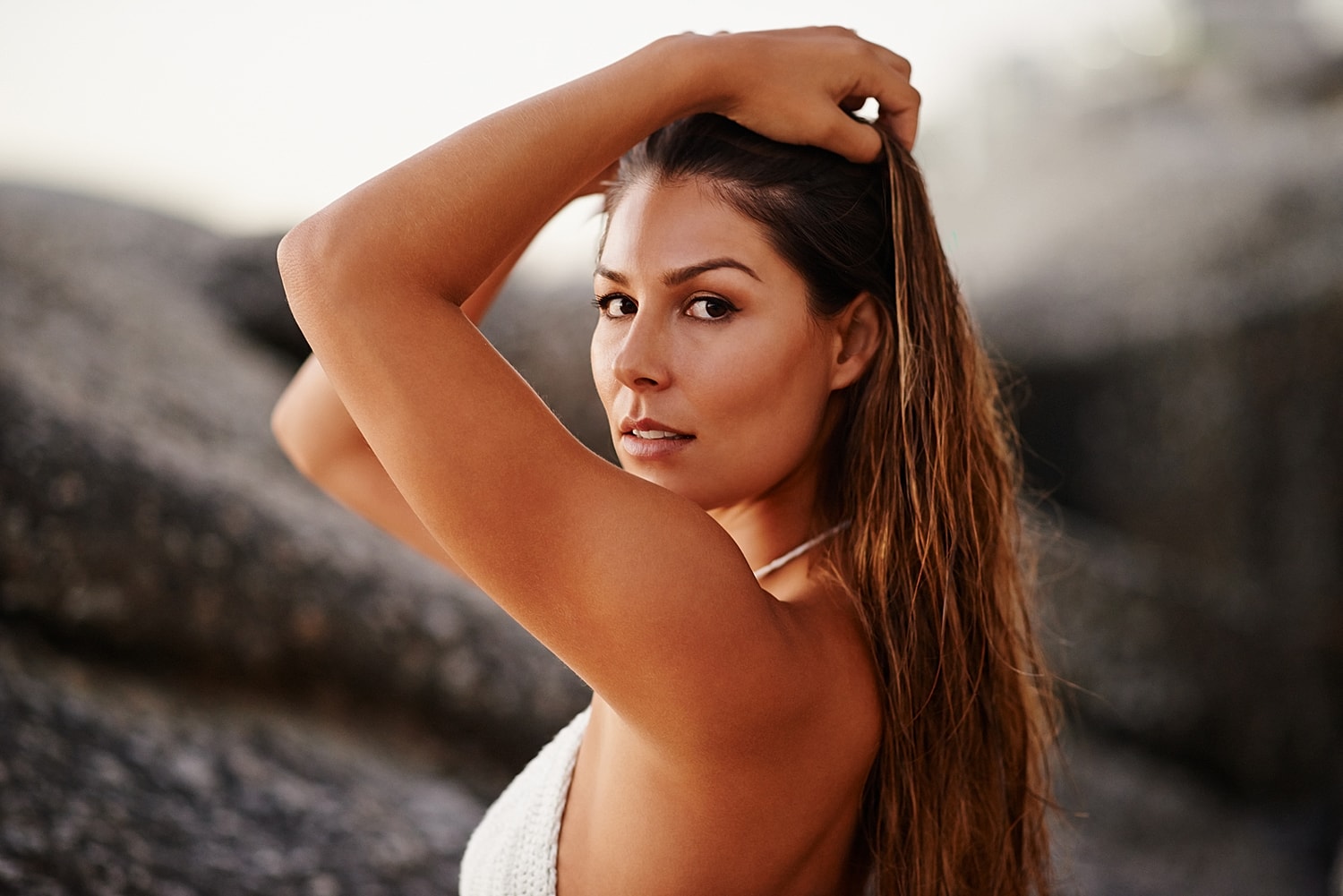 Woman posing against rocky background at sunset.