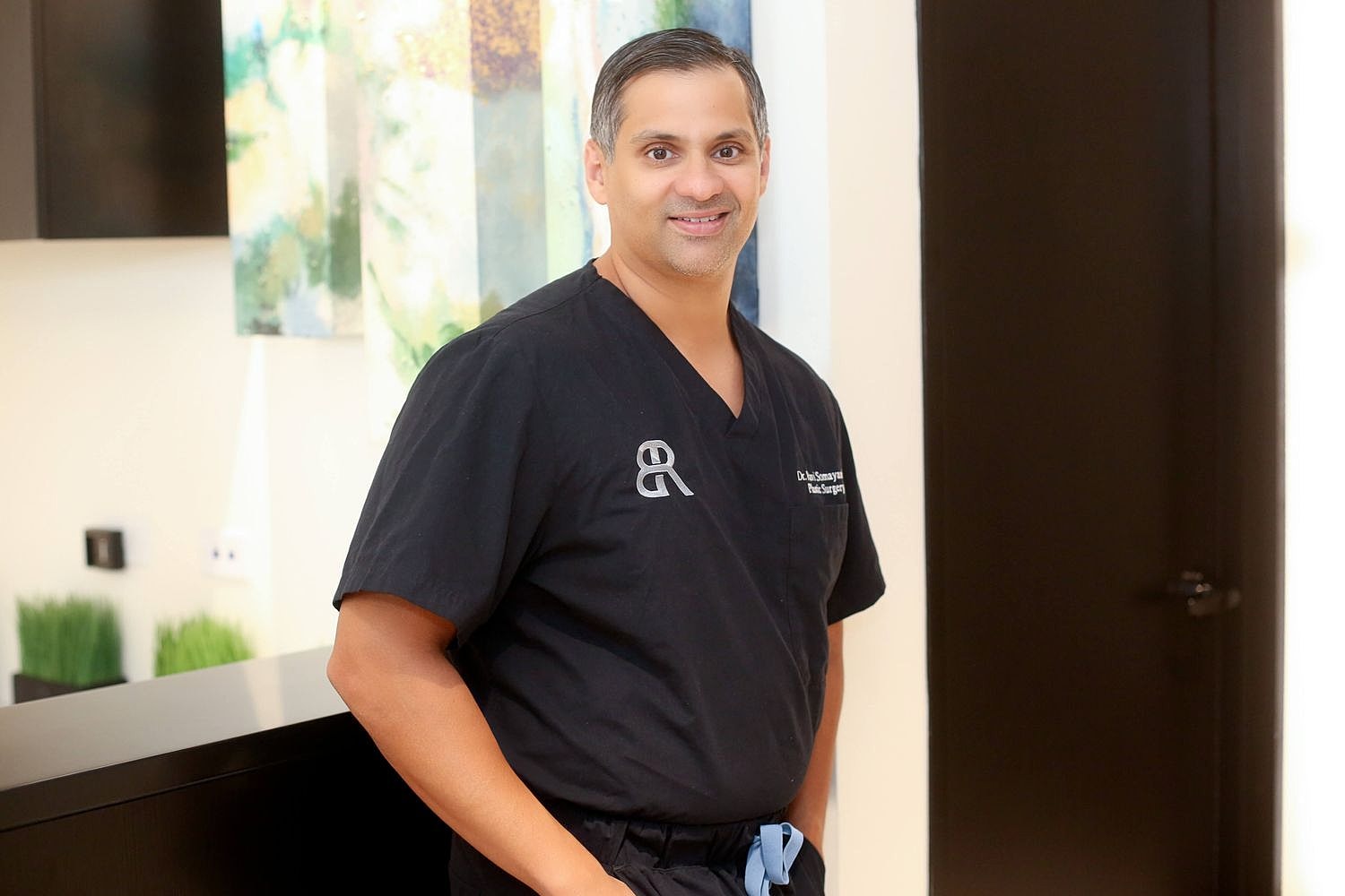 Smiling doctor in black scrubs at clinic.