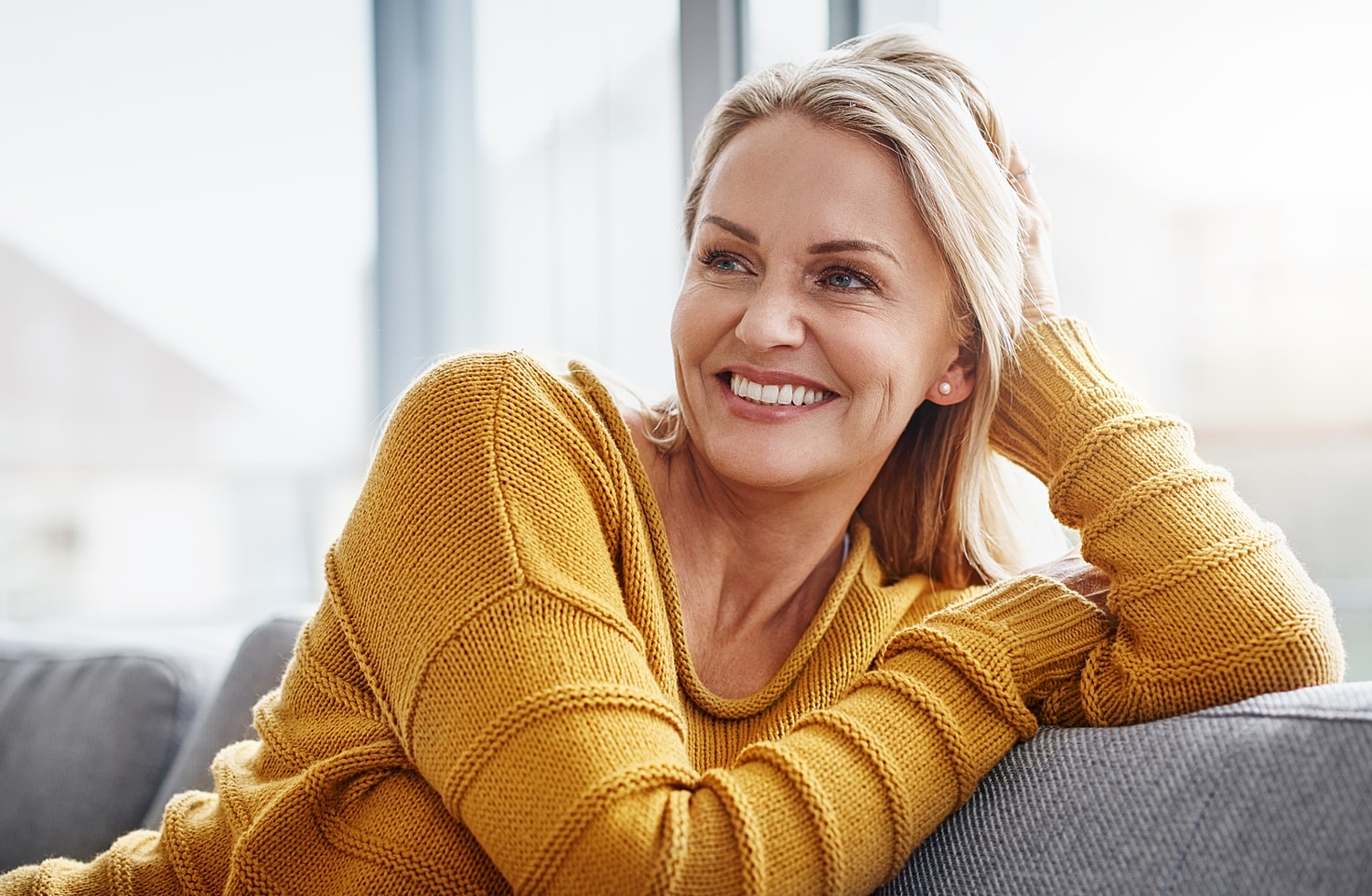 Smiling woman in yellow sweater relaxing indoors
