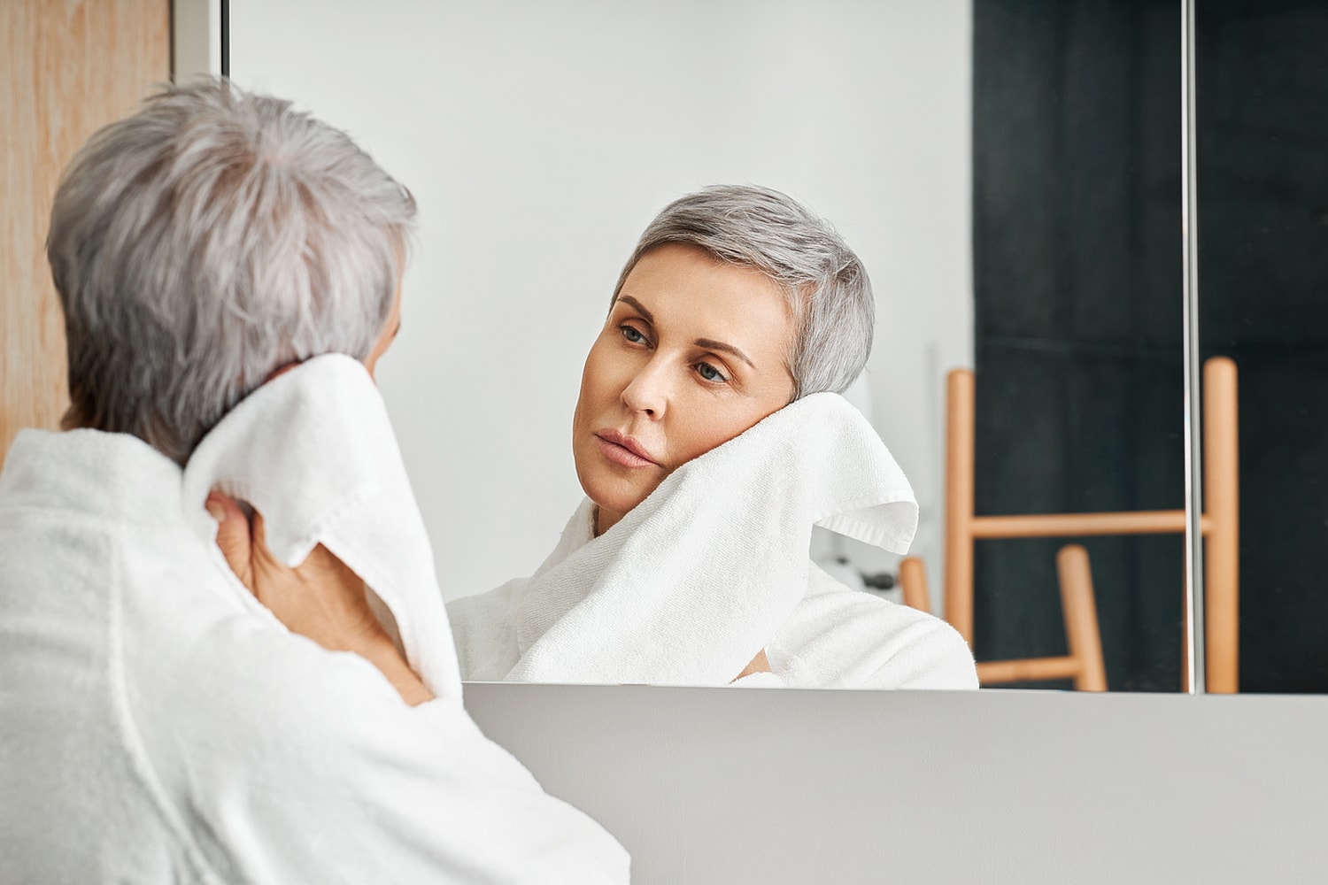 Woman in towel looking at her reflection.