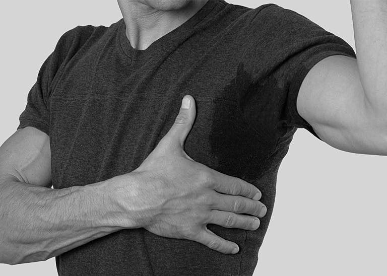 Man with wet shirt gripping his chest.