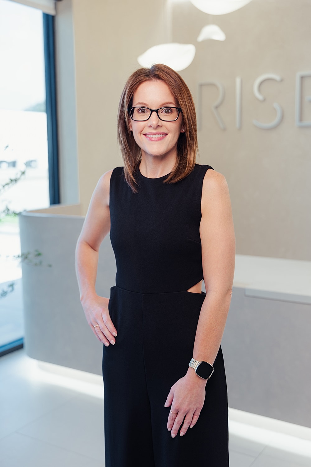 Smiling woman in professional attire, modern office setting.