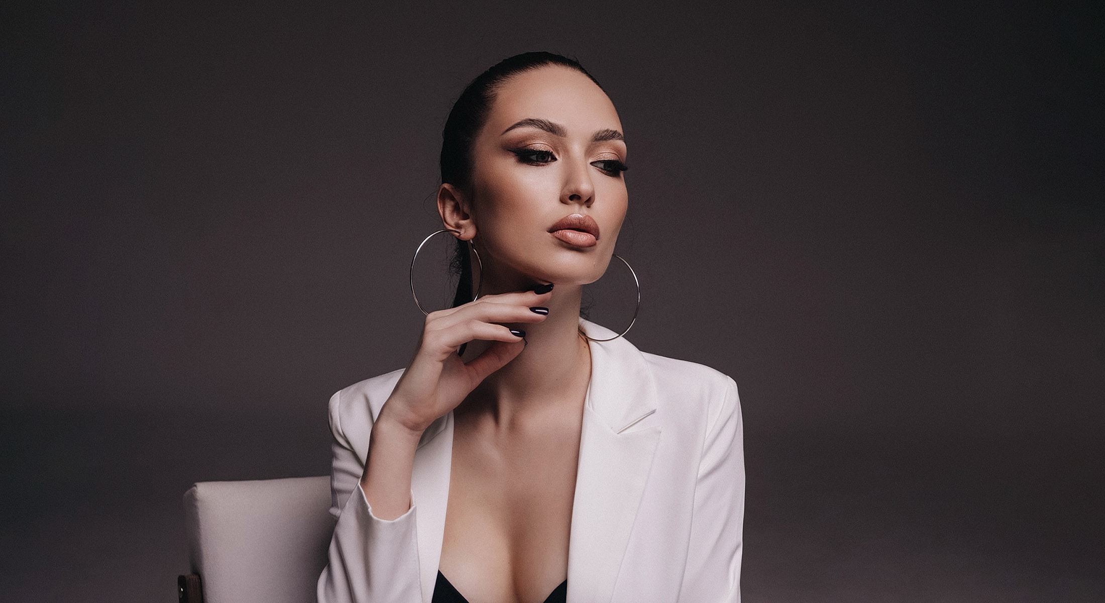 Woman with hoop earrings in elegant attire.